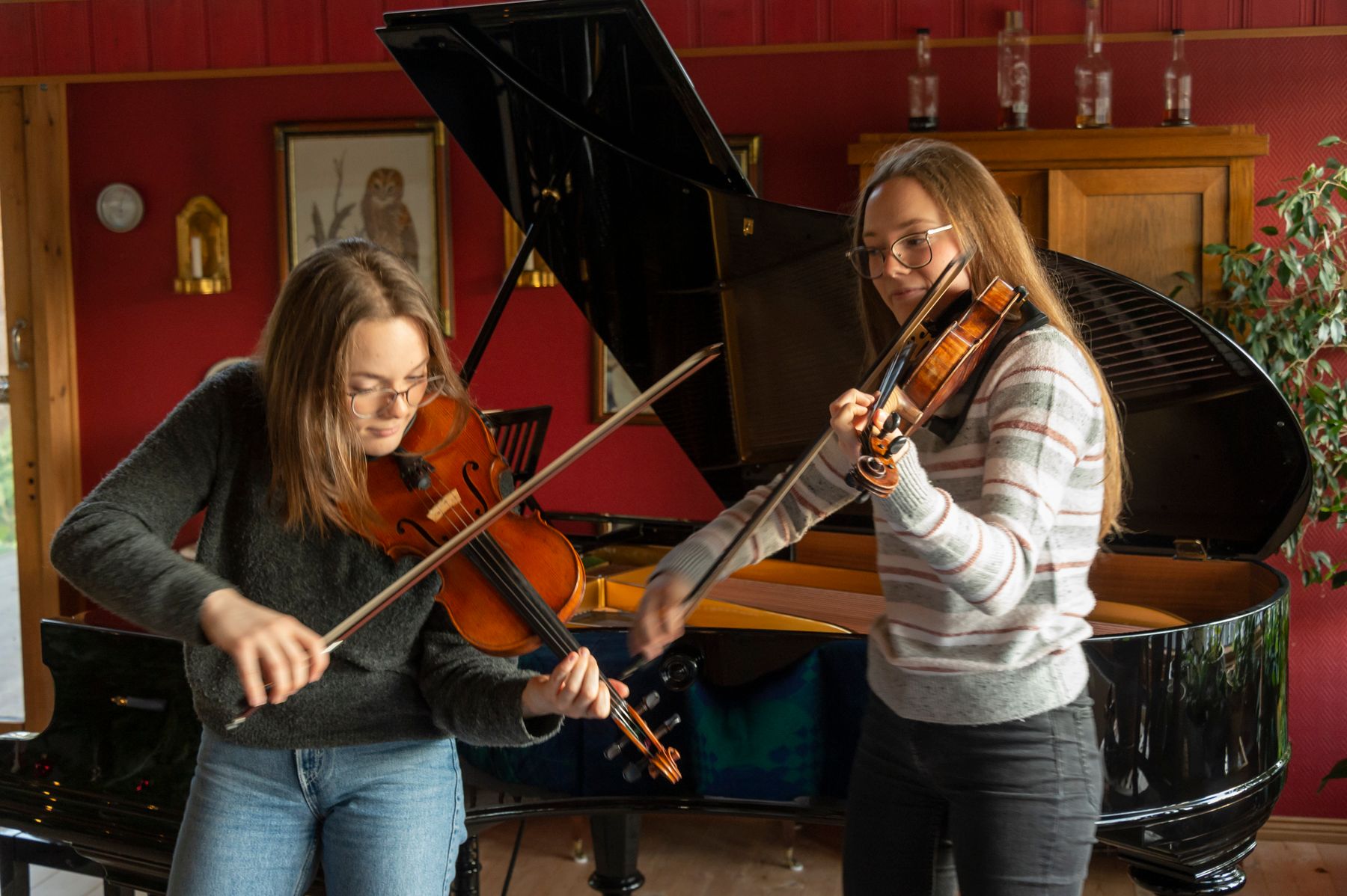 To unge kvinner som spiller fiolin foran et åpent flygel