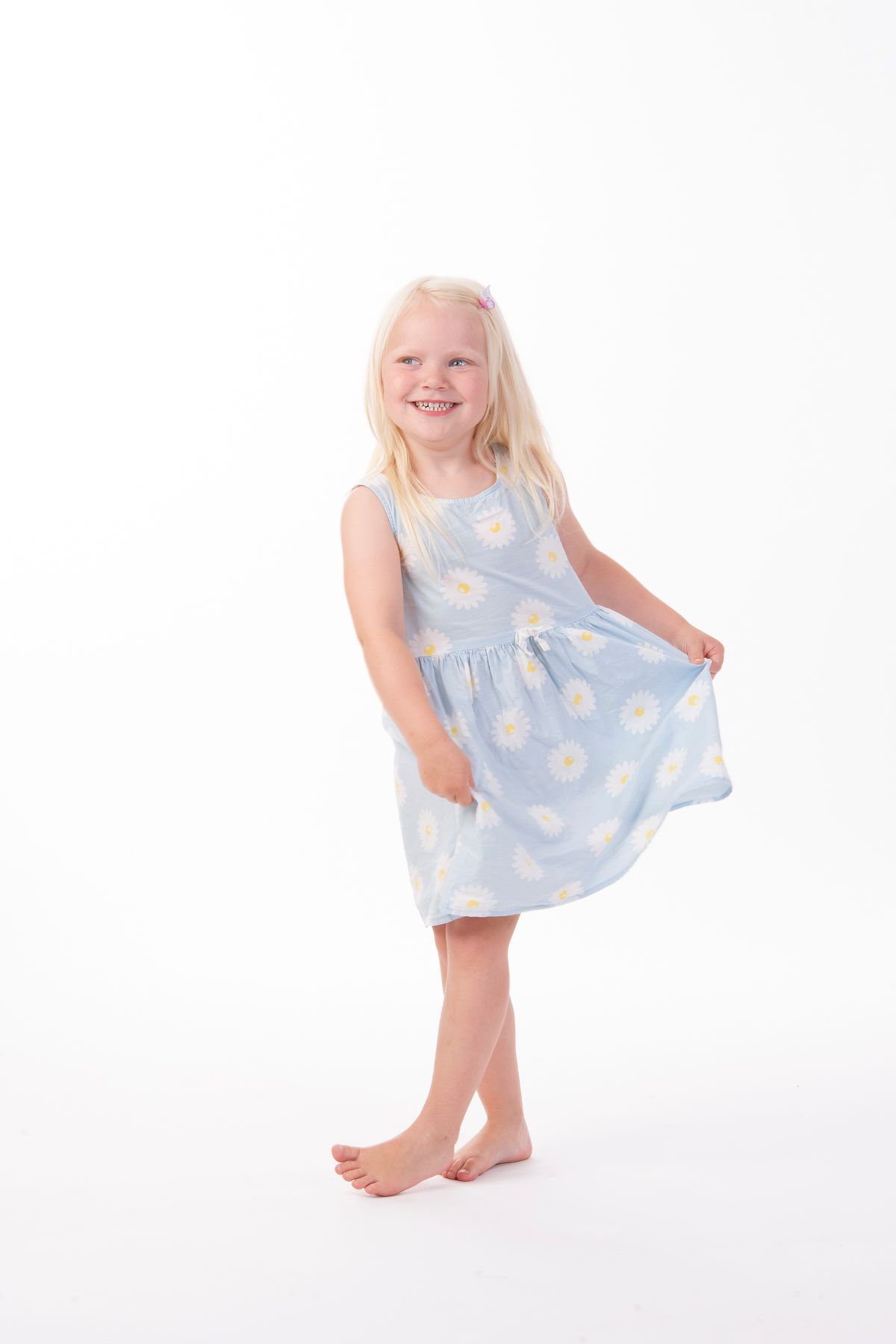 En liten jente med lyseblå kjole med hvit bakgrunn