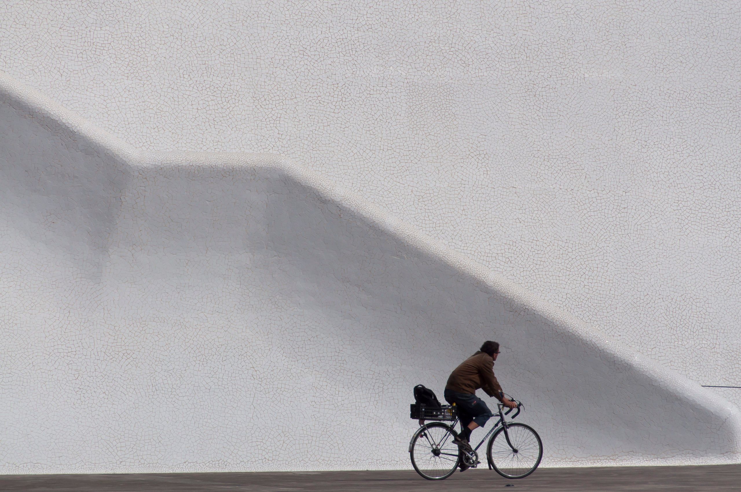 En som sykler foran en hvit vegg med en linje som ligner på en stor trapp