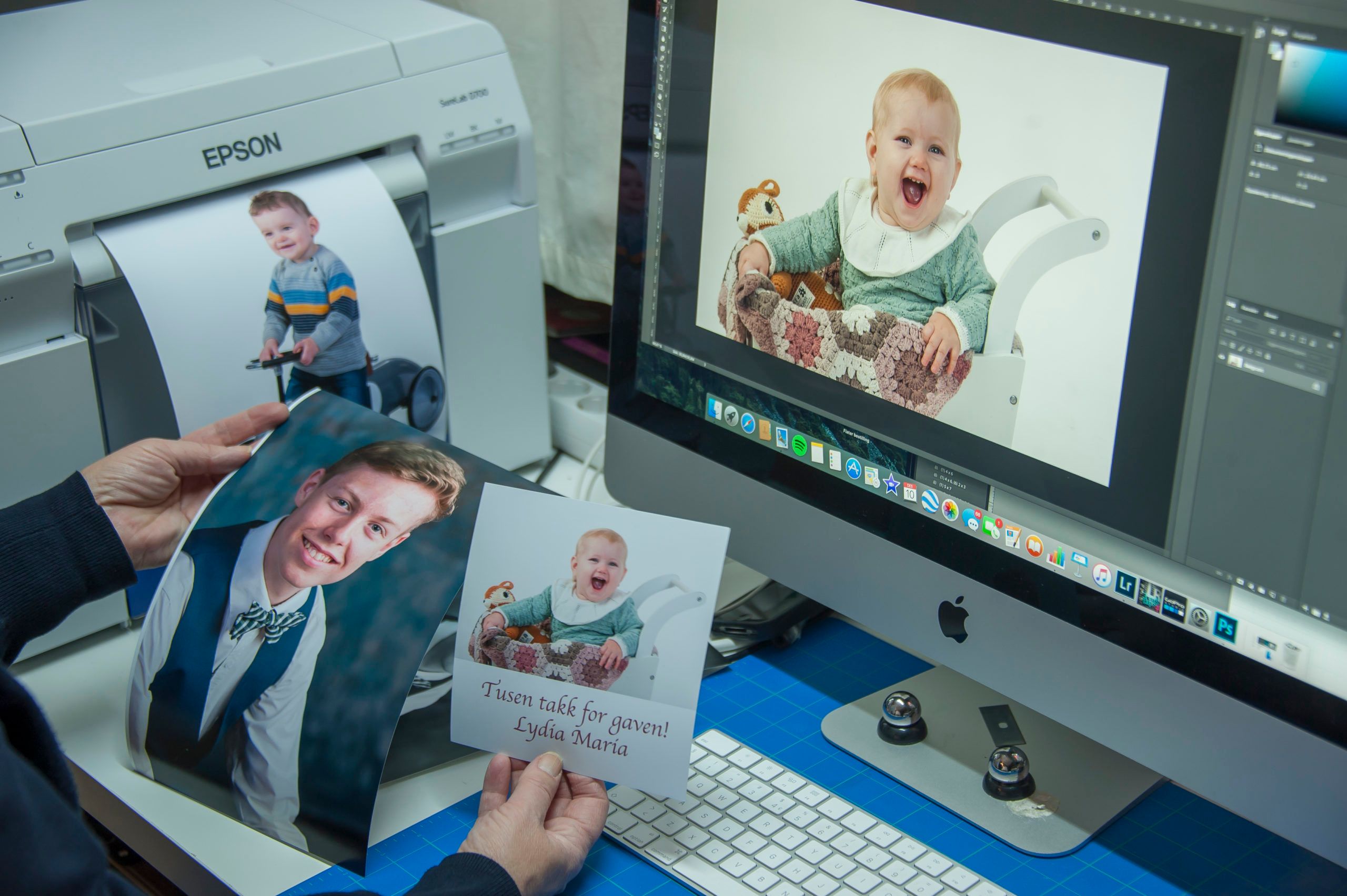 To hender som holder opp forskjellige fotoprint, en skjerm med et fotografi og en printer med et bilde på vei ut i bakgrunnen