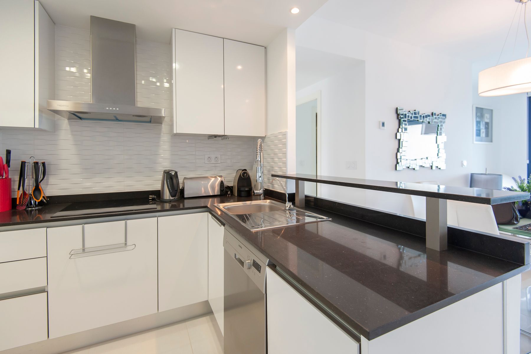 Et kjøkken med glatte hvite fronter og svart marmorlignende benkeplate