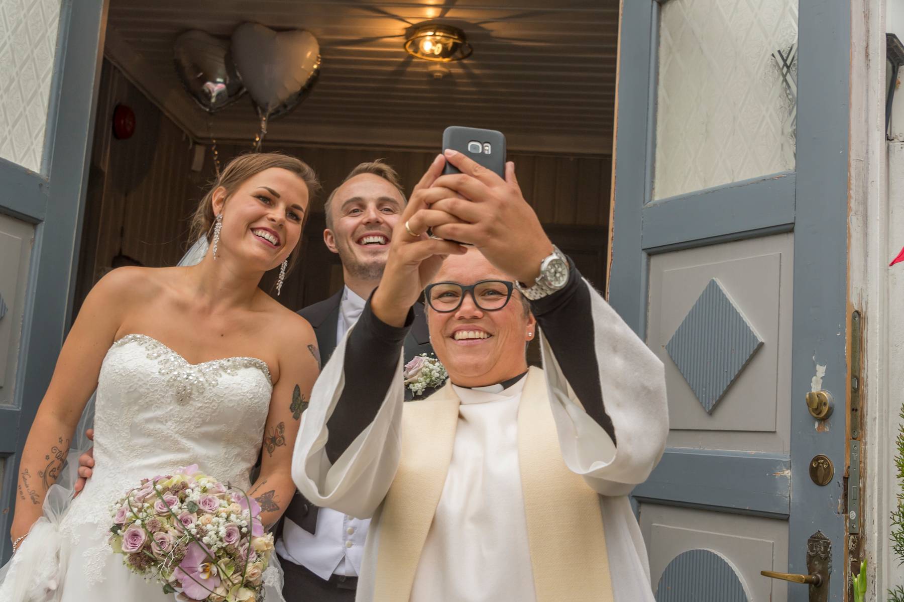 En prest som tar en selfie av seg og et brudepar