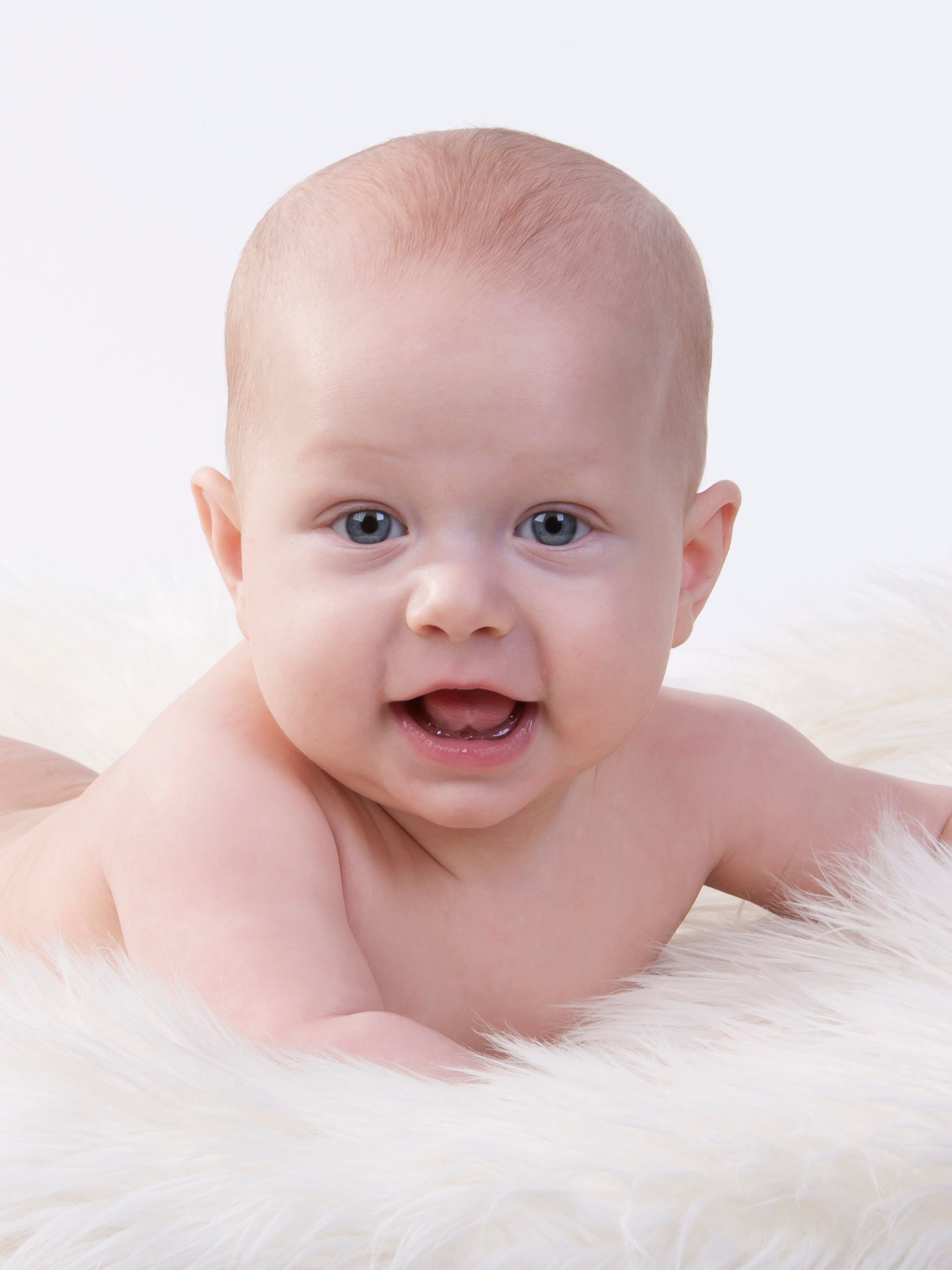 En baby som ligger på et saueskinn med hvit bakgrunn