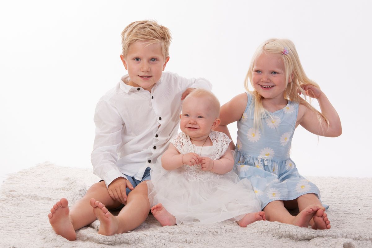 Tre barn sittende på gulvet med hvit bakgrunn
